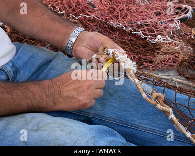 Fisherman rammendo la sua rete da pesca. Primo piano dettaglio. Foto Stock