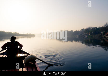 Silhouette di boatsman remare nella yamuna ganga river al mattino. La mattina presto giri in barca sul santo fiumi sacri dell India sono un comune Foto Stock