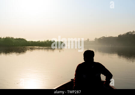 Silhouette di boatsman remare nella yamuna ganga river al mattino. La mattina presto giri in barca sul santo fiumi sacri dell India sono un comune Foto Stock