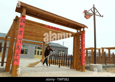 (190622) -- YINCHUAN, 22 giugno 2019 (Xinhua) -- abitante Sun Jinhua esegue la pulizia nella parte anteriore della sua nuova casa, anche un agritainment spot, a Xingwuying villaggio di Gaoshawo township di Yanchi County, a nord-ovest della Cina di Ningxia Hui Regione autonoma, 27 maggio 2019. Situato sul bordo meridionale del deserto Maowusu, Yanchi contea era una volta colpito dalla povertà e ha sofferto di desertificazione. Ma dopo anni di sforzi, l'ambiente vi è stata ripristinata e la contea ha scosso anche fuori dalla povertà. (Xinhua/Zheng Wei) Foto Stock