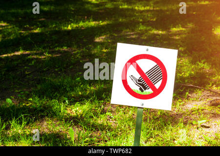 Il segno proibitivo sull'etichetta non a piedi il prato - closeup contro tha prato in presenza di luce solare. Primo piano di non camminare il segno di prato Foto Stock