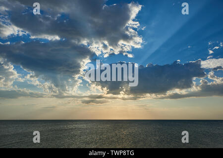 Il tramonto. Raggi del sole attraverso le nuvole sul mare Foto Stock