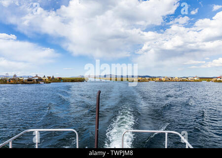 Viaggiando su una barca attraverso un canale nel totora canne sul lago Titicaca, Perù, Sud America Foto Stock