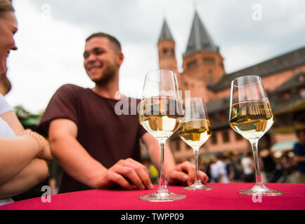 Mainz, Germania. Il 22 giugno, 2019. Di fronte ai visitatori ci sono tre bicchieri di vino su un tavolo, sullo sfondo è possibile vedere la Cattedrale. Centinaia di migliaia di visitatori sono attesi alla Quattro giorni di 'Johannisnacht' festival nel 2019. Il folk festival è stato tenuto in onore del Johannes Gutenberg fin dal 1968. Credito: Andreas Arnold/dpa/Alamy Live News Foto Stock