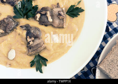 Sulla tavola in una ciotola di zuppa di zucca con pancetta fritta, noci, semi di zucca e prezzemolo. Foto Stock