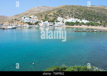Una vista sulla baia sulla splendida isola greca di Sikinos. La spiaggia di sabbia conduce al porto delle isole dove gli edifici imbiancati fiancheggiano il porto. Foto Stock