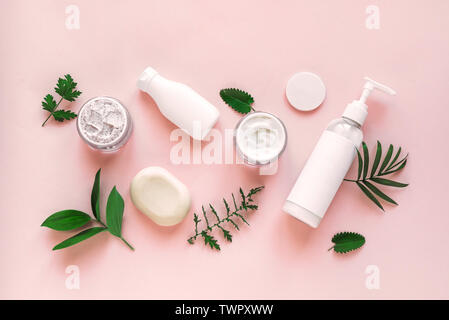 Cosmetici naturali e foglie verdi su sfondo rosa, vista dall'alto, piatto laici. Organici naturali skincare, bio ricerca e stile di vita sano concetto. Foto Stock