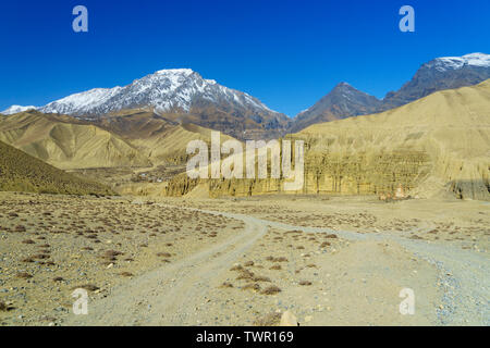 Pista sterrata che porta al villaggio di Ghemi, parzialmente visibile in lontananza. Mustang Superiore regione, Nepal. Foto Stock