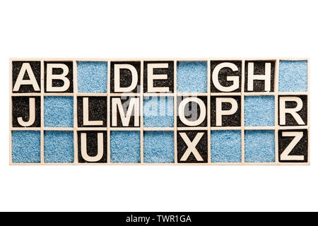 In un cassone di raccolta con blu e nero Sabbia decorativa disposti compensato le lettere dalla A alla Z individualmente con lettere mancanti in vista dall'alto su bianco. Foto Stock