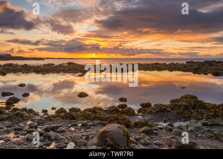 Perfetto pool di marea la riflessione di un vivido il tramonto. Riflessioni perfetta del dipinto il cielo al tramonto lungo la spiaggia. Tramonto colorato, speculare del cielo. Foto Stock