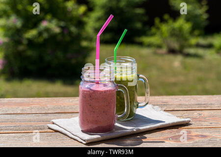 Vegano sano frullato verde con spinaci, Apple, sedano, kiwi, Bruxelles germoglio, avocado e berry smoothie alla fragola e banana in vasetti di vetro, Foto Stock