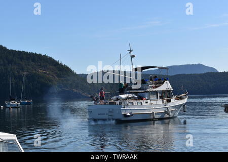 Un motoscafo lasciando Cowichan Bay marina su un tranquillo e soleggiato al mattino. Foto Stock