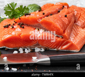 Crudo fresco re i filetti di salmone su pietra naturale con le erbe aromatiche e i condimenti Foto Stock