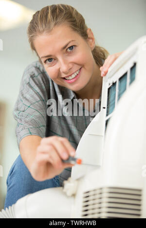 Giovane donna di pulizia condizionatore di aria in ambienti interni Foto Stock