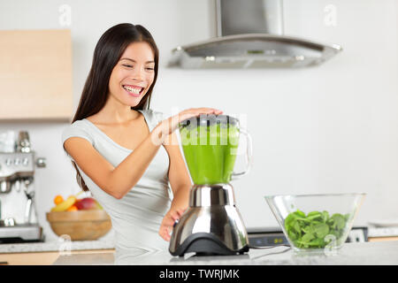 Frullato vegetale donna verde blending frullati con blender home in cucina. Mangiare sano stile di vita concetto Ritratto di giovane e bella donna preparando drink con spinaci, carote, sedano ecc. Foto Stock