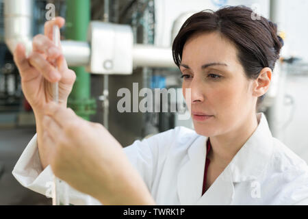 Donna in camice da laboratorio lavora nella fabbricazione di prodotti lattiero-caseari Foto Stock