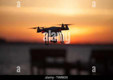 Un fantoccio DJI 3 Pro Drone sfiorando con un tramonto colorato come sfondo Foto Stock