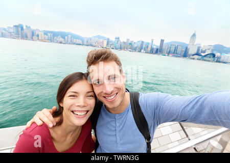 Selfie - turista giovane tenendo selfportrait immagine fotografia di Hong Kong gode di escursioni a Tsim Sha Tsui Promenade e Avenue of Stars e nel Porto Victoria, Kowloon, Hong Kong. Concetto di viaggio. Foto Stock
