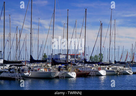 Yacht a vela con alti alberi in un ambiente marino contro il cielo blu con nuvole bianche Foto Stock