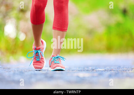 Jogging donna con gambe atletiche e scarpe da corsa. A piedi femmina sul sentiero nella foresta in uno stile di vita sano concetto con close up sulle scarpe da corsa. Atleta femminile formazione pareggiatore all'esterno. Foto Stock