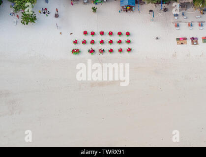 Vista superiore del rosso tavoli e sedie verde sulla bianca spiaggia presso il ristorante del resort Foto Stock