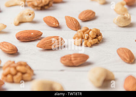 Assortimento di dadi bianco su un tavolo di legno. Anacardi, nocciole, noci, mandorle Foto Stock