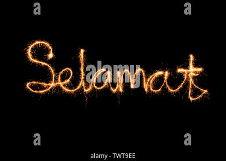 Selamat scritto in sparkle fuoco su sfondo nero Foto Stock