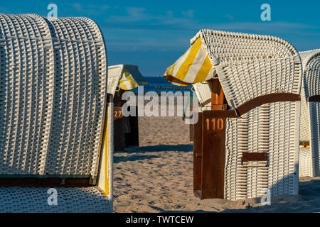 Bianco con tetto di sedie da spiaggia in vimini in golden luce del sole su una spiaggia in Kühlungsborn Foto Stock