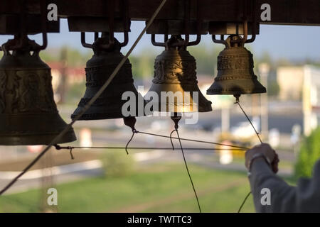 Chiesa di carillon e nodo di corde in mano di campana-suoneria sul campanile della Cattedrale della Trinità, durante le campane a celebrare la Pasqua. Ucraina, Donetsk, un Foto Stock