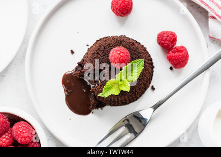 Cioccolato Torta di lava sulla piastra con lamponi freschi e foglia di menta. Vista superiore Foto Stock