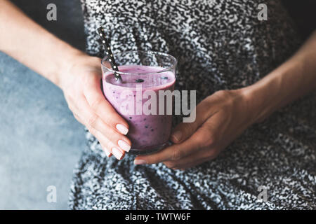 Bicchiere di viola frullato mirtillo nella donna con le mani in mano. Pulire mangiare vegetariano, dieta vegana concetto. Immagine dai toni Foto Stock