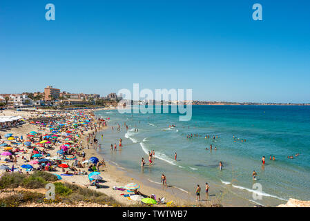 Occupato Mediterranean Beach a Playa Mil Palmeras, Pilar de la Horadada, Alicante, Spagna, Europa. Sun colorate sfumature di blu del cielo e del mare. Costa Blanca Foto Stock