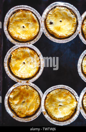 Chiuso mini quiche quiche farcite con carne e funghi, frutti, ciliegie su uno sfondo scuro. vista dall'alto. Foto Stock