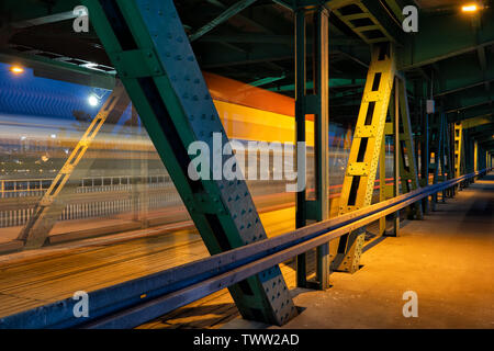 Ponte di notte con il tram sentieri di luce dietro il telaio di metallo a Varsavia in Polonia. Foto Stock