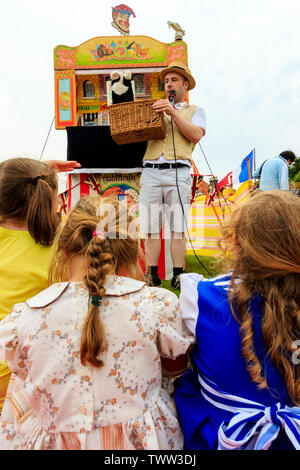 Broadstairs Dickens festival. Vista sopra la spalla di giovani bambini in età vittoriana costume Dickensian guardando un punzone e Judy show all'esterno. Foto Stock