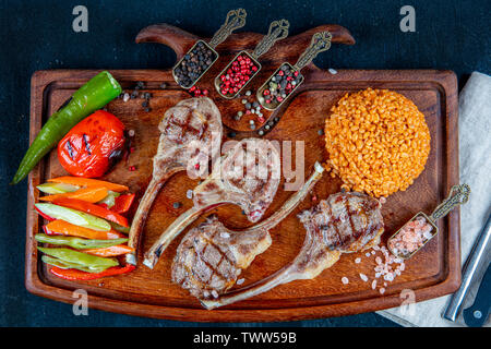 Costolette di agnello grigliate sul tagliere con verdure alla griglia. Vista superiore spazio copia sullo sfondo di legno. Ristorante Halal concetto. Foto Stock