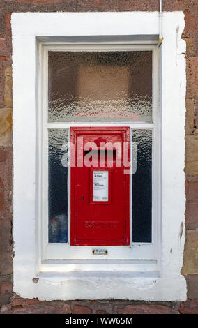 Un rosso post box in una finestra con un bordo bianco in Cromarty, Black Isle, Ross and Cromarty, Scotland, Regno Unito. Foto Stock