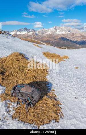 Escursionista zaino lasciato nella neve dopo una lunga escursione nelle Dolomiti. Autunno in montagna, i colori dell'autunno in alpine. McKinley Zaino grigio. Foto Stock