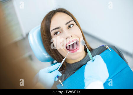 Ragazza sorridente considera i denti mentre è seduto in poltrona odontoiatrica presso il medico. Foto Stock