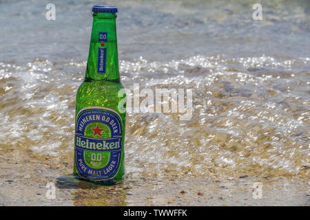 Heineken alcol zero bottiglia di birra sulla sabbia dal mare. Sunny View di analcolici birra chiara su un 33cl bottiglia di vetro parzialmente sommerso sulla spiaggia sabbiosa. Foto Stock