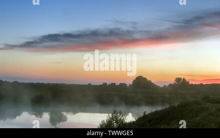 Tramonto su un piccolo lago con la nebbia sopra l'acqua. Foto Stock