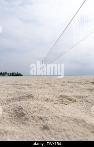 Focus sulla sabbia in primo piano. Campo da pallavolo sulla spiaggia di un isola tropicale Foto Stock