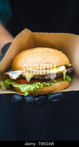 Grandi hamburger di manzo e uovo vicino fino in mano dello chef Foto Stock