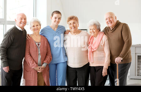 Giovani caregiver con gruppo di alti persone nella casa di cura Foto Stock