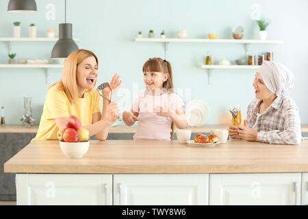 Donna matura dopo la chemioterapia con la sua famiglia per divertirsi in cucina a casa Foto Stock