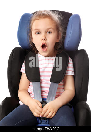 Scioccato bambina allacciata in sicurezza in auto la sede contro uno sfondo bianco Foto Stock
