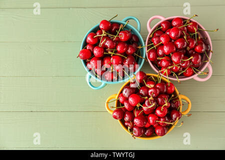 Pentole con i dolci di ciliegia matura su sfondo di legno Foto Stock