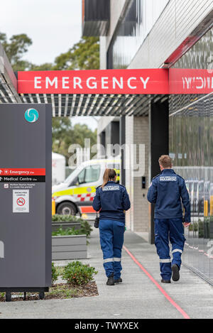 Due giovani bianco maschio e femmina paramedico ambulanza ufficiali a piedi verso un ambulanza e segno di emergenza a Sydney è di nuovo spiagge settentrionali ospedale Foto Stock