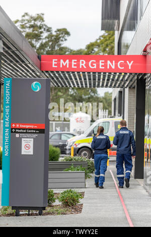 Due giovani bianco maschio e femmina paramedico ambulanza ufficiali a piedi verso un ambulanza e segno di emergenza a Sydney è di nuovo spiagge settentrionali ospedale Foto Stock