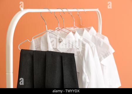 Elegante uniforme scolastica appesa sulla cremagliera contro il colore di sfondo Foto Stock